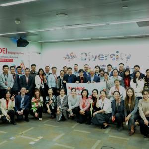 A large group photo of people stood in front of the Diversity Equity Inclusion wall display 