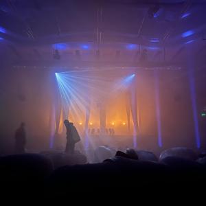 dark image with colored lights and people with bean bags