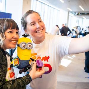 two volunteers taking a photo together whilst holding a toy