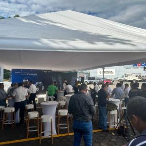 People attending an outdoor event, stood underneath a canopy 