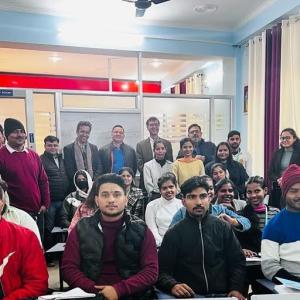 Students sat at desks with other students stood behind them 