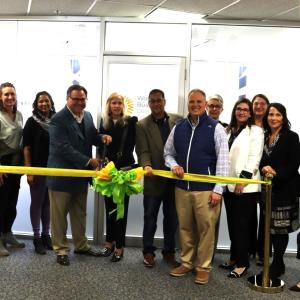 People standing together behind a ribbon about to be cut