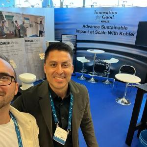 2 people smiling in front of Innovation for Good sign