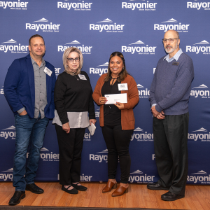 Four people standing together, one holding a check