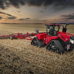 Red tractor on a field with a sunset behind it