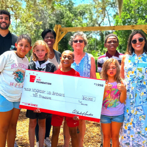 A group of children and adults posing and smiling with an oversized check