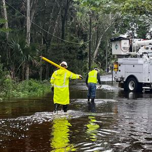Workers in reflective jackets wading through water on a road