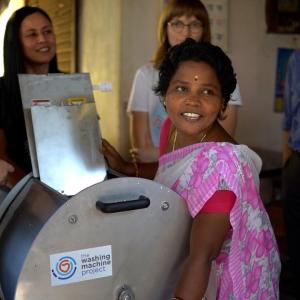 people smiling around a washing machine