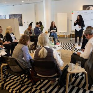 People sitting in a circle listening to someone giving a presentation