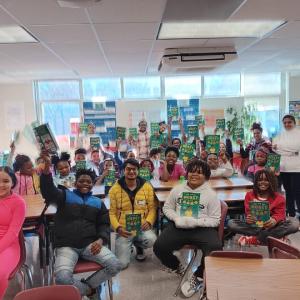 Students holding up books in classroom