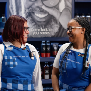 Two Bath & Body Works employees smiling at each other in a store