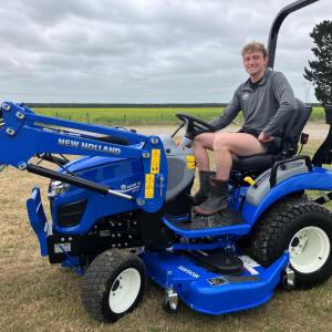 A person sitting on a blue tractor in a field