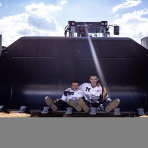 Two young people sat on a piece of agricultural equipment 