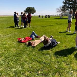 Three people lying on the grass looking up