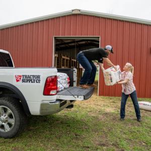 A man helping a woman unload product from a Tractor Supply truck