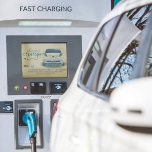 white car in front of a white Fast Charging kiosk