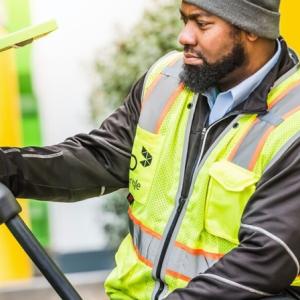 worker in a safety vest plugging in an electric bus