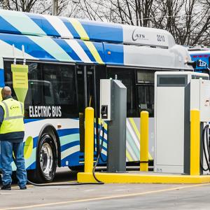 workers in safety gear charging electric buses