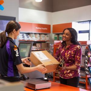 FedEx employee hands box to smiling customer