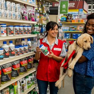 Tractor Supply employee helping a customer who is holding her dog