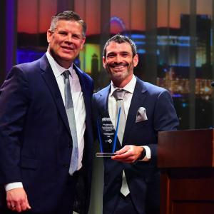 Two people stood together posing for a photo, one person holding an award