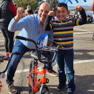 A man and a young boy pose with a bike.