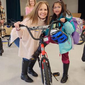 An Arrow employee poses with a little girl and a bike