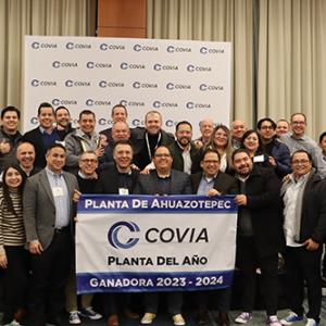 A group of people posed behind a Covia banner