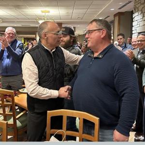 Two people shaking hands in front of people applauding