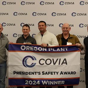 Five people smiling behind a Covia banner