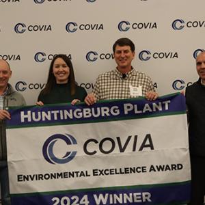 Four people smiling behind a Covia banner