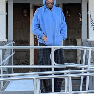 Roy shown in front of his house on the wheelchair ramp.