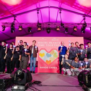 People posing on a stage, holding up a heart