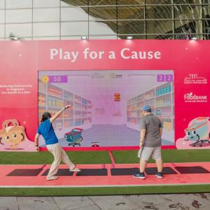 Two adults playing in front of a "Play for a Cause" sign
