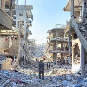 Man walks through street lined with destroyed buildings