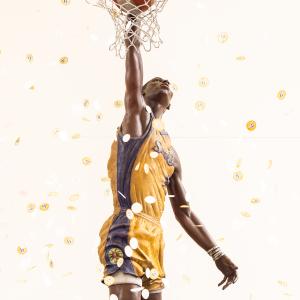 Close-up view of bronze Los Angeles Sparks basketball player Lisa Leslie statue reaching through the hoop as gold confetti falls around it.
