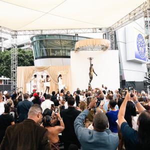 Large crowd photographs the unveiling of Lisa Leslie's bronze Los Angeles Sparks statue during an outdoor event.