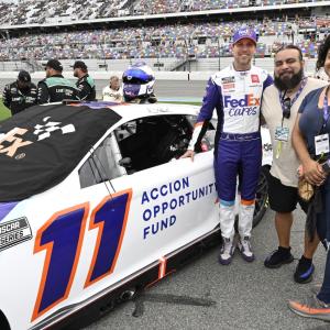 Mayra Hernandez, Jesse Iniguez and Denny Hamlin stand next to the FedEx 11 race car
