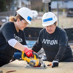 2 arrow employees using a saw