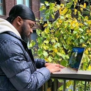 Jeremiah on a balcony writing on laptop