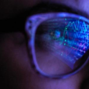 Person wearing glasses reflecting numbers and graphs