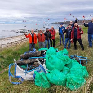 A group of people standing in a field together by a beach