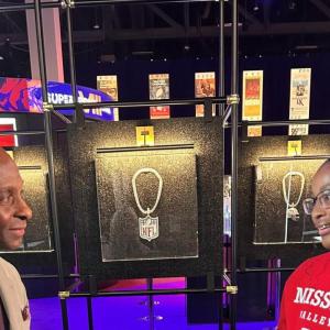 Two people stood either side a framed NFL pendant 