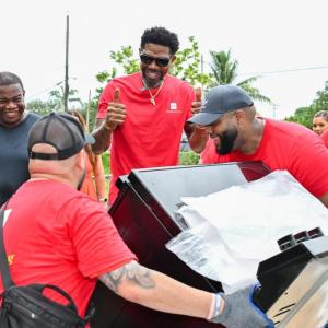 Volunteers in red shirts carrying a new oven