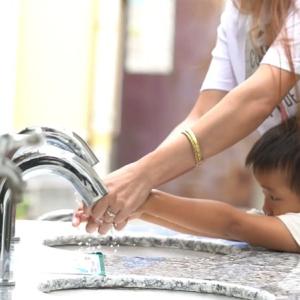 An adult helping a child wash their hands