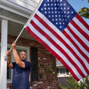 person putting American flag on house