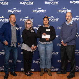Four people standing together, one holding a check