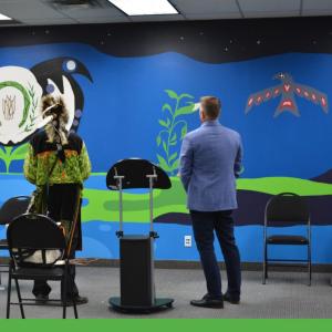 Two people shown from the back, looking at a large mural