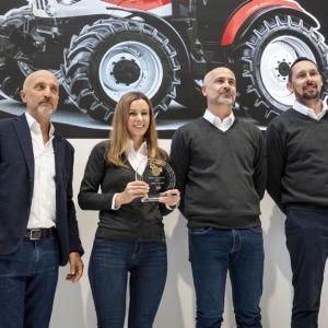 Four people posing together, one holding an award.
