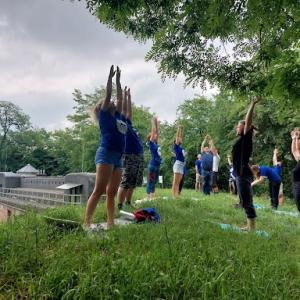 A group outside on grass, reaching their hands up